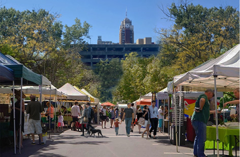 people walking amongst vendor tents lined up on either side of a walkway.  